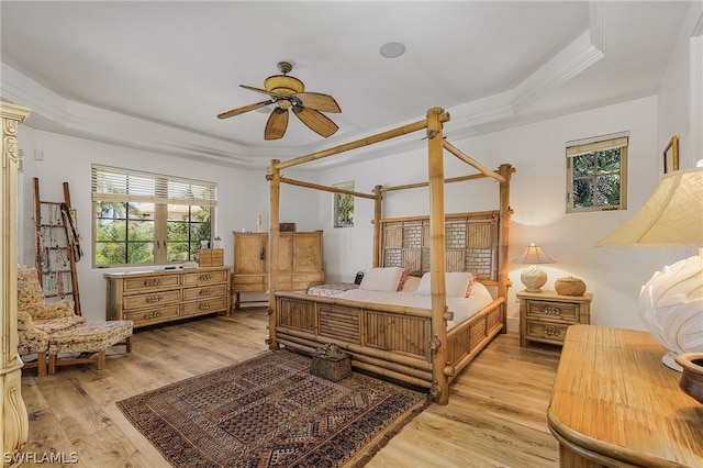 bedroom featuring a tray ceiling, light hardwood / wood-style floors, crown molding, and ceiling fan