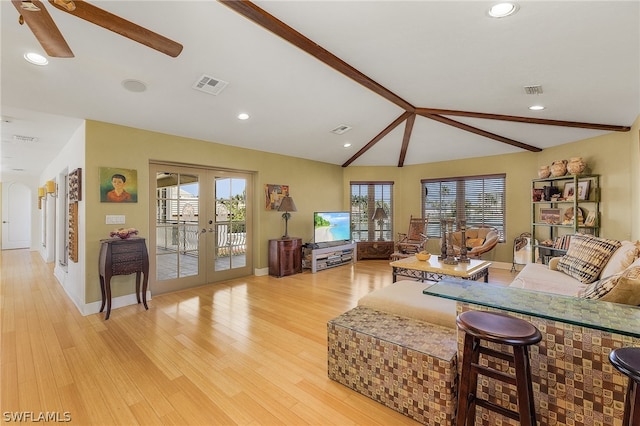 living room with plenty of natural light, ceiling fan, vaulted ceiling, and light hardwood / wood-style flooring