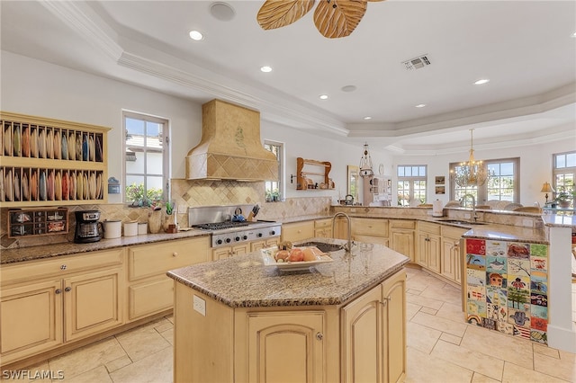 kitchen featuring an island with sink, a tray ceiling, backsplash, and custom exhaust hood