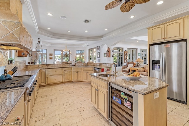 kitchen with appliances with stainless steel finishes, wine cooler, sink, ceiling fan, and a raised ceiling