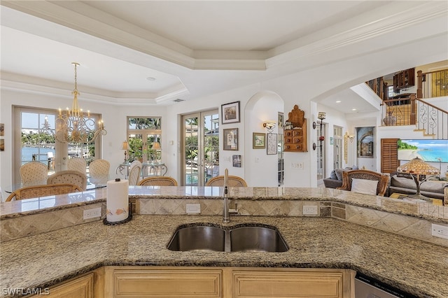 kitchen featuring a raised ceiling, sink, stone countertops, and a chandelier