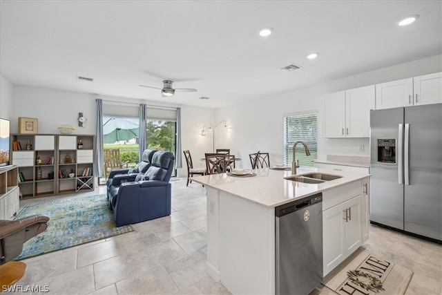 kitchen with white cabinets, stainless steel appliances, a center island with sink, ceiling fan, and sink