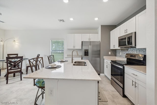 kitchen with stainless steel appliances, a center island with sink, tasteful backsplash, a breakfast bar area, and sink