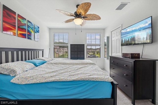 bedroom featuring visible vents, a ceiling fan, and light carpet