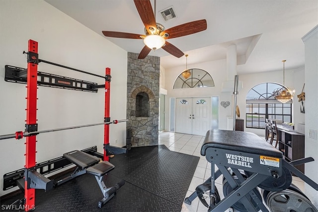 exercise area featuring french doors, light tile patterned flooring, and ceiling fan with notable chandelier