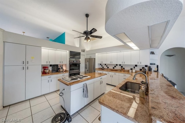 kitchen featuring stainless steel fridge, white cabinetry, a kitchen island, and sink