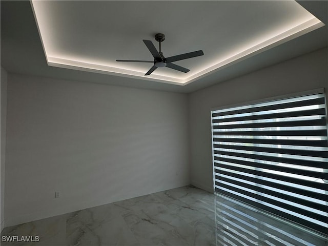 empty room with a raised ceiling and ceiling fan