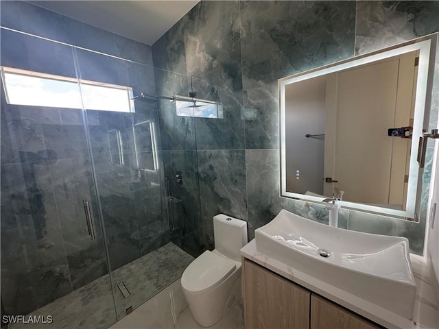 bathroom featuring vanity, toilet, a shower with door, and tile walls