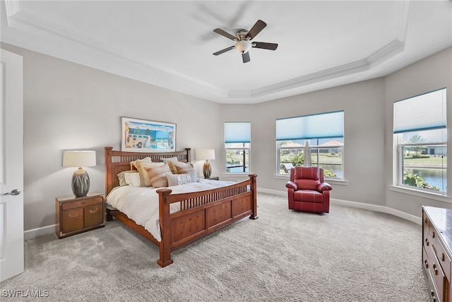 carpeted bedroom featuring a raised ceiling, ceiling fan, and crown molding