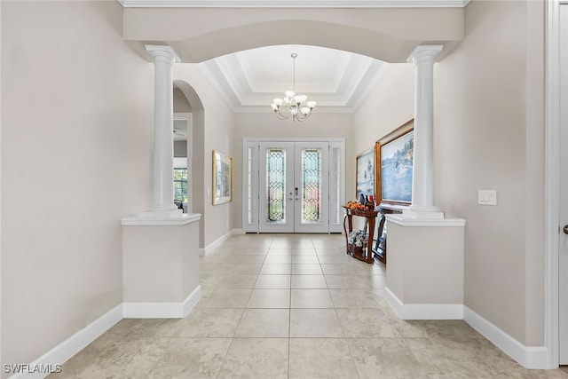 tiled entrance foyer featuring french doors, a tray ceiling, an inviting chandelier, and crown molding