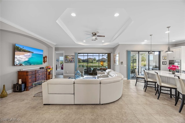 living room with ceiling fan, a healthy amount of sunlight, and a tray ceiling