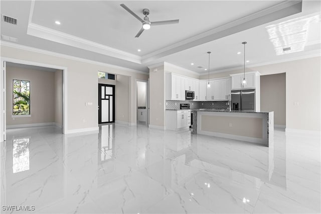 kitchen featuring appliances with stainless steel finishes, a tray ceiling, a kitchen island, white cabinets, and hanging light fixtures