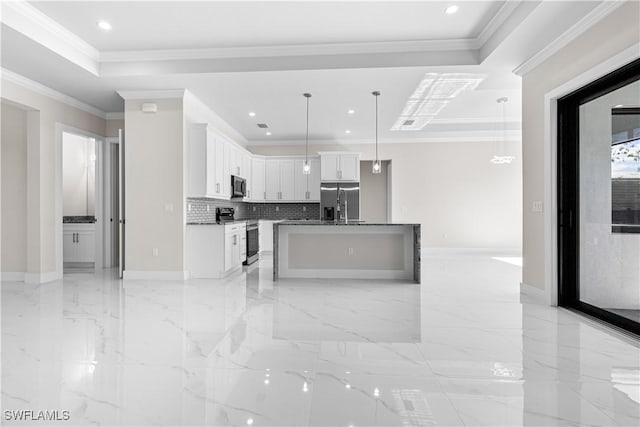 kitchen featuring appliances with stainless steel finishes, hanging light fixtures, white cabinets, a raised ceiling, and a kitchen island