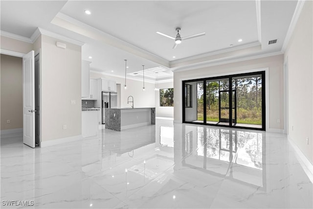 unfurnished living room with sink, crown molding, ceiling fan, and a raised ceiling