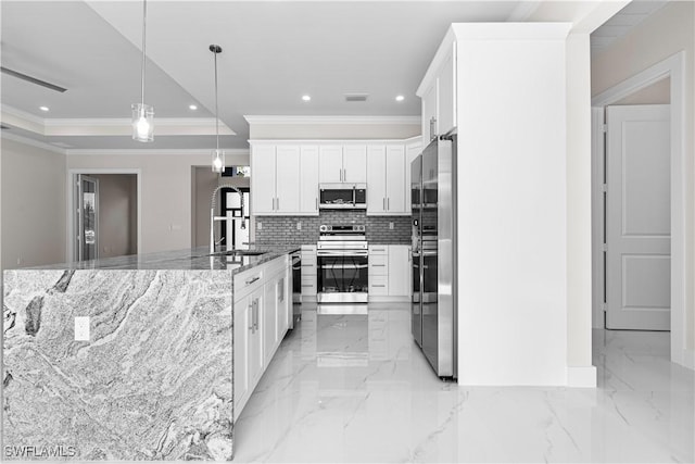 kitchen featuring dark stone countertops, appliances with stainless steel finishes, pendant lighting, white cabinets, and a kitchen island with sink