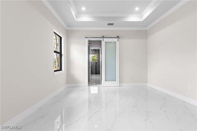 empty room with a tray ceiling, a barn door, and ornamental molding