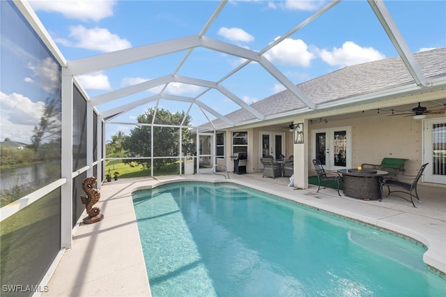 view of swimming pool featuring french doors, ceiling fan, glass enclosure, and a patio area