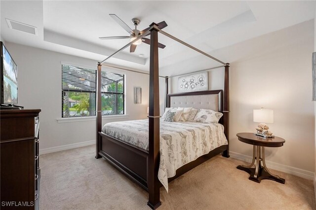 carpeted bedroom featuring a raised ceiling and ceiling fan