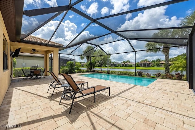 view of pool with a lanai, ceiling fan, a water view, and a patio