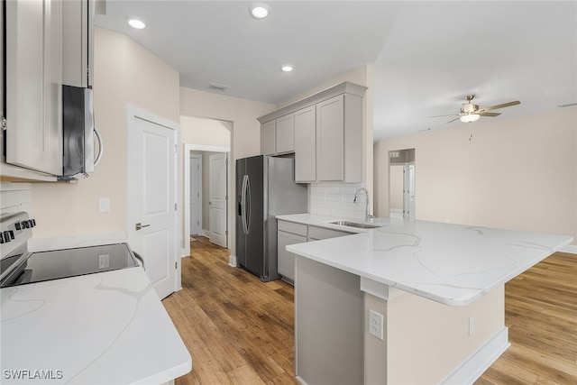 kitchen featuring stainless steel appliances, kitchen peninsula, sink, ceiling fan, and light hardwood / wood-style floors