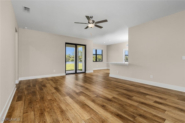 spare room featuring wood-type flooring, visible vents, ceiling fan, and baseboards