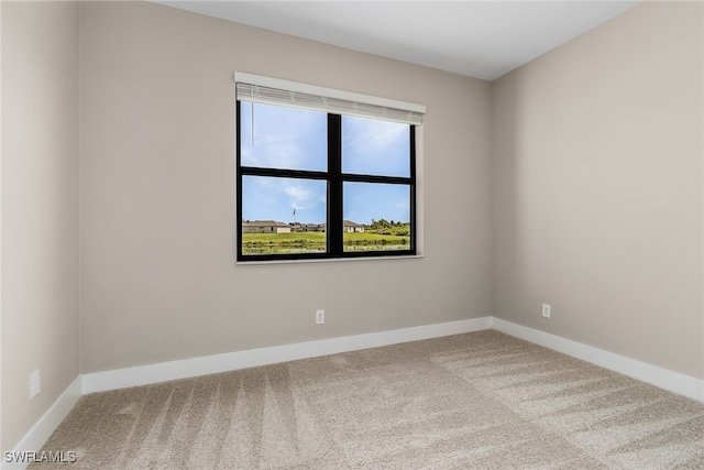 carpeted empty room featuring baseboards