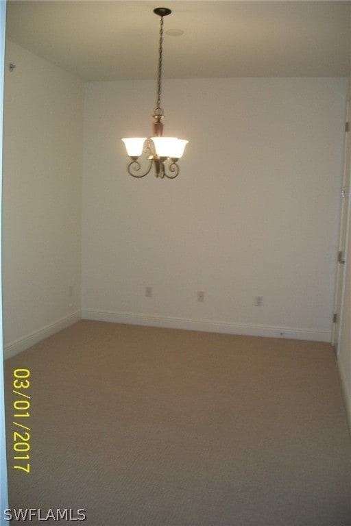 spare room with carpet floors and a chandelier