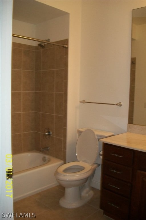 full bathroom with tile floors, tiled shower / bath, toilet, and vanity