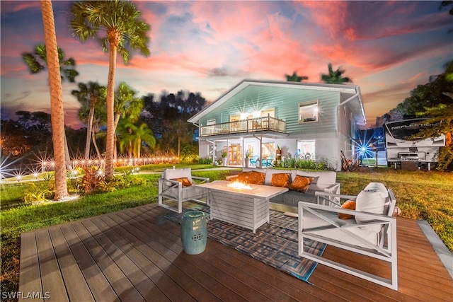 deck at dusk featuring an outdoor fire pit and a lawn