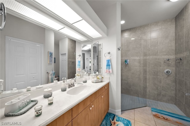 bathroom featuring tiled shower, vanity, and tile flooring