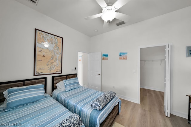 bedroom featuring ceiling fan, a closet, hardwood / wood-style floors, and a spacious closet