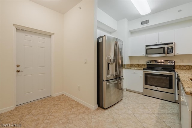 kitchen featuring light stone counters, white cabinets, light tile floors, and appliances with stainless steel finishes