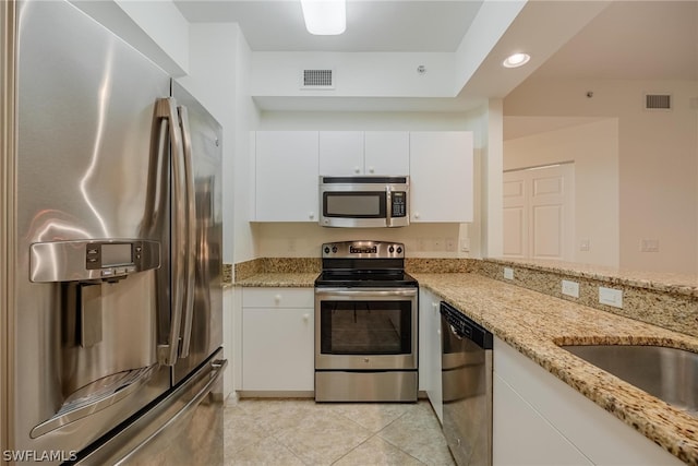 kitchen with light tile floors, light stone counters, white cabinetry, and appliances with stainless steel finishes