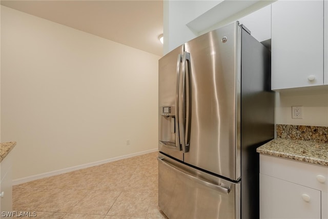 kitchen featuring white cabinetry, light tile flooring, stainless steel refrigerator with ice dispenser, and light stone counters