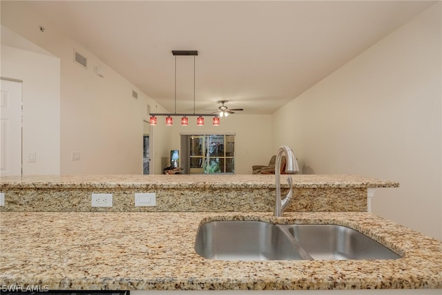 kitchen with ceiling fan, sink, decorative light fixtures, and light stone countertops