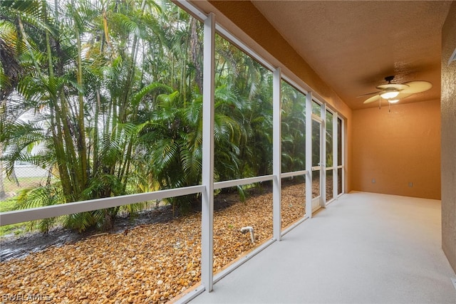 unfurnished sunroom with ceiling fan