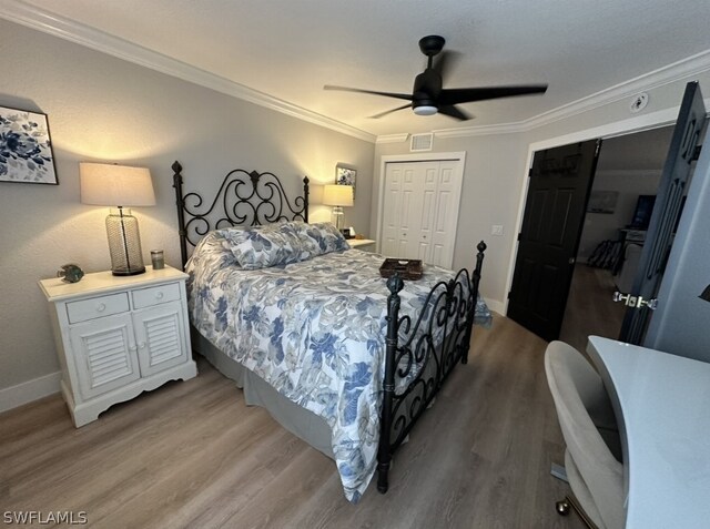 bedroom featuring hardwood / wood-style flooring, ornamental molding, ceiling fan, and a closet