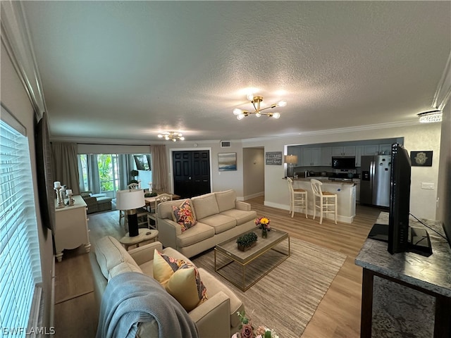 living room with a textured ceiling, light wood-type flooring, and crown molding