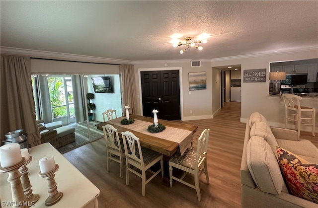 dining space featuring an inviting chandelier, a textured ceiling, dark hardwood / wood-style floors, and crown molding