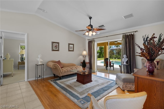 living room with lofted ceiling, ornamental molding, ceiling fan, and light tile floors