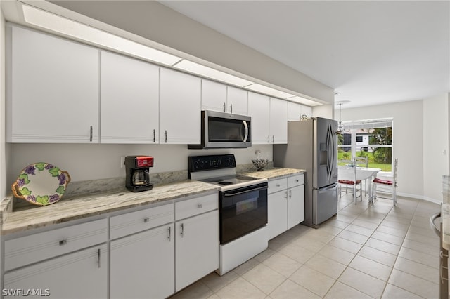 kitchen with white cabinets, light stone countertops, light tile floors, and stainless steel appliances