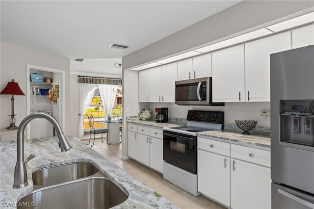 kitchen with light tile flooring, light stone counters, sink, white cabinets, and appliances with stainless steel finishes