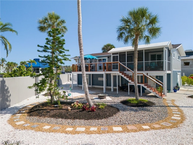 rear view of property featuring a sunroom, a deck, and a patio