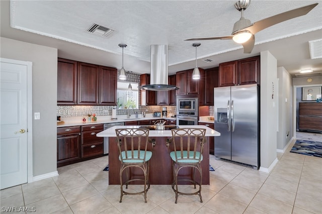 kitchen with light countertops, appliances with stainless steel finishes, visible vents, and island range hood