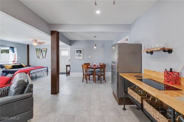 kitchen with black electric stovetop, hanging light fixtures, a ceiling fan, freestanding refrigerator, and open floor plan