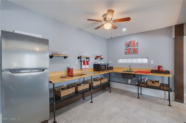 interior space featuring black microwave, ceiling fan, a sink, and freestanding refrigerator