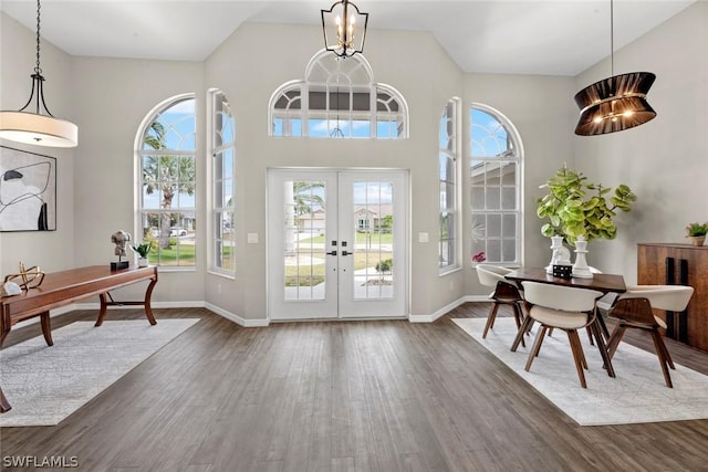 entrance foyer with plenty of natural light, dark wood-type flooring, french doors, and a notable chandelier