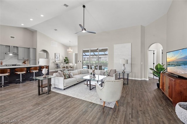 living room with hardwood / wood-style flooring, ceiling fan with notable chandelier, and high vaulted ceiling