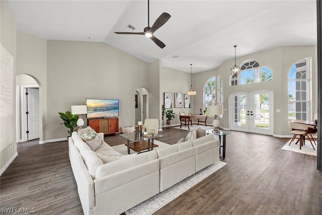 living room featuring french doors, ceiling fan with notable chandelier, high vaulted ceiling, and dark wood-type flooring