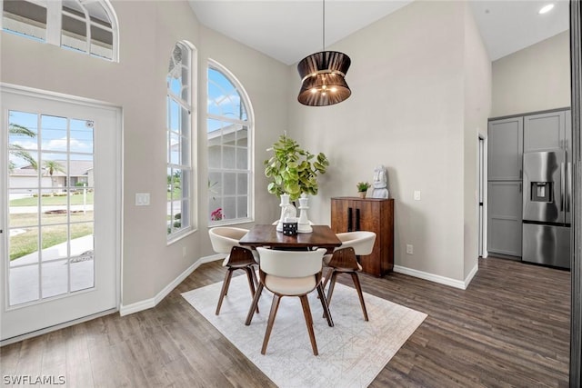 dining room featuring dark hardwood / wood-style flooring, high vaulted ceiling, a healthy amount of sunlight, and a notable chandelier